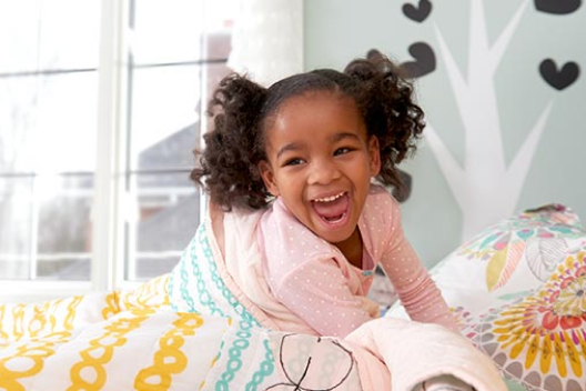 A kid laughing and playing in bed