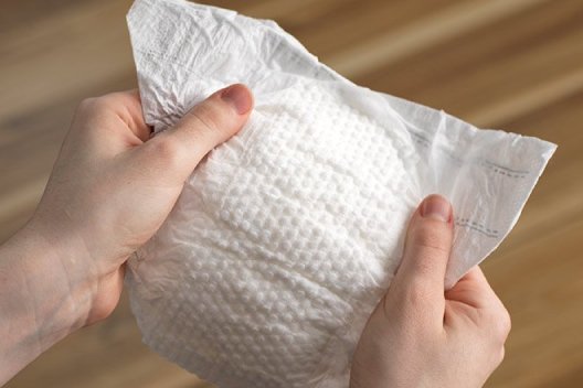 Hands holding a Huggies Little Snugglers Diaper showing the Gentle Absorb liner
