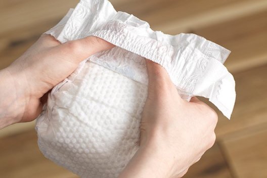 Hands holding a Huggies Little Snugglers Diaper showing the Pocketed Waistband