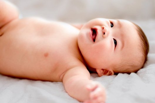 A diapered baby laying on a white blanket