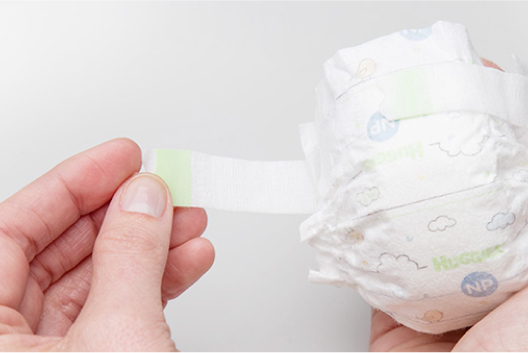 A hand demonstrating narrow fasteners on Huggies Little Snugglers Nano Preemie Diapers