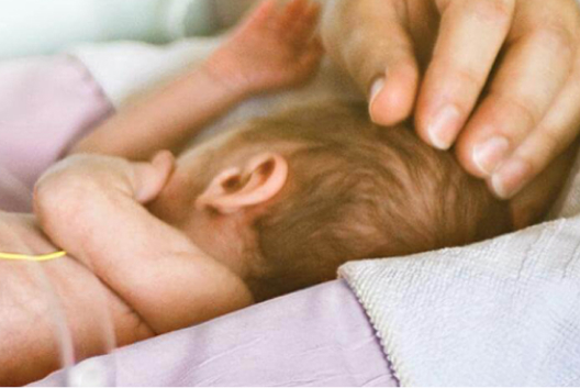 Hand placed on the head of a newborn baby