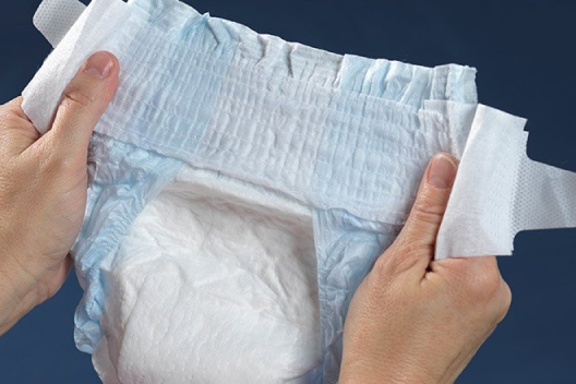 Hands holding Huggies Overnites Diaper showing its DryTouch® Liner
