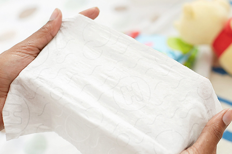Hands holding a Huggies disposable baby wipe