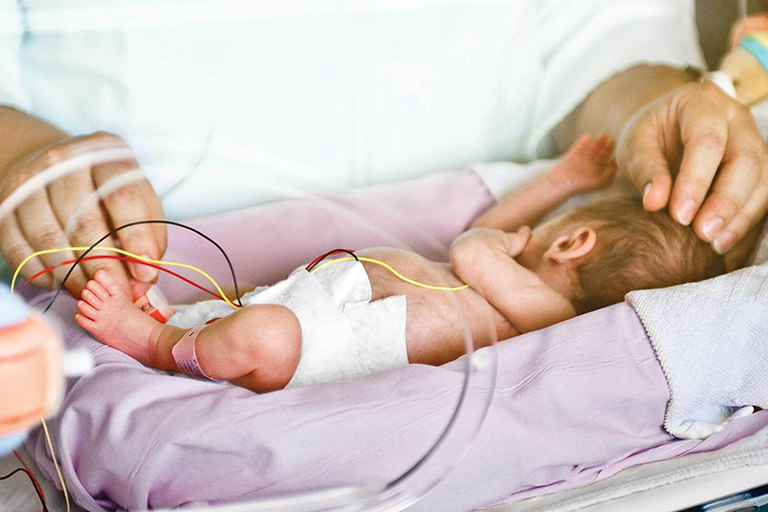 Healthcare professional taking care of a baby lying in bed of an NICU
