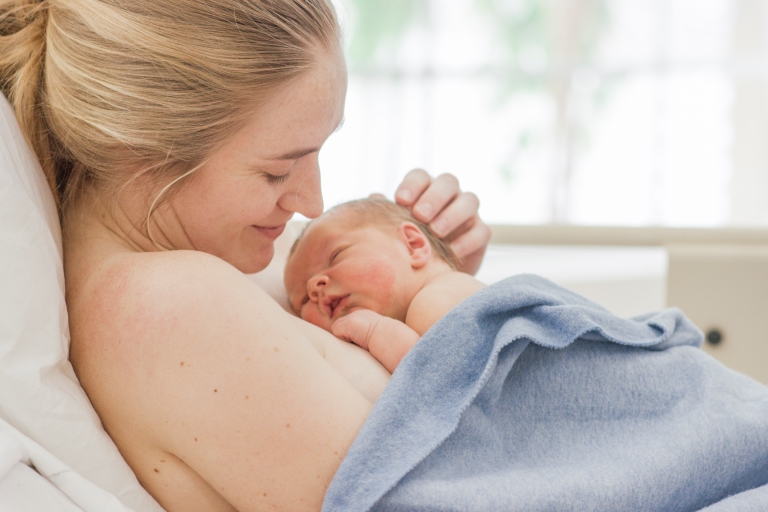 A mother hugging a newborn baby skin to skin in NICU