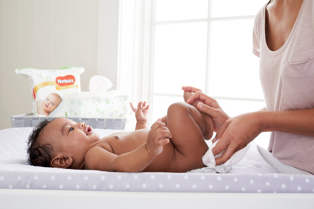 A Mother wiping a baby with Huggies wipes
