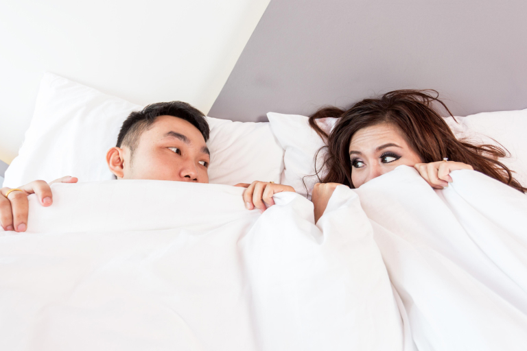 Couple lying in bed, planning for pregnancy by tracking ovulation days