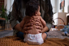 mom holding baby sitting upright with diaper rash
