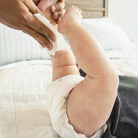 Baby boy eating pasta, with dermatologist-tested, hypoallergenic Huggies® Skin Essentials™ wipes 